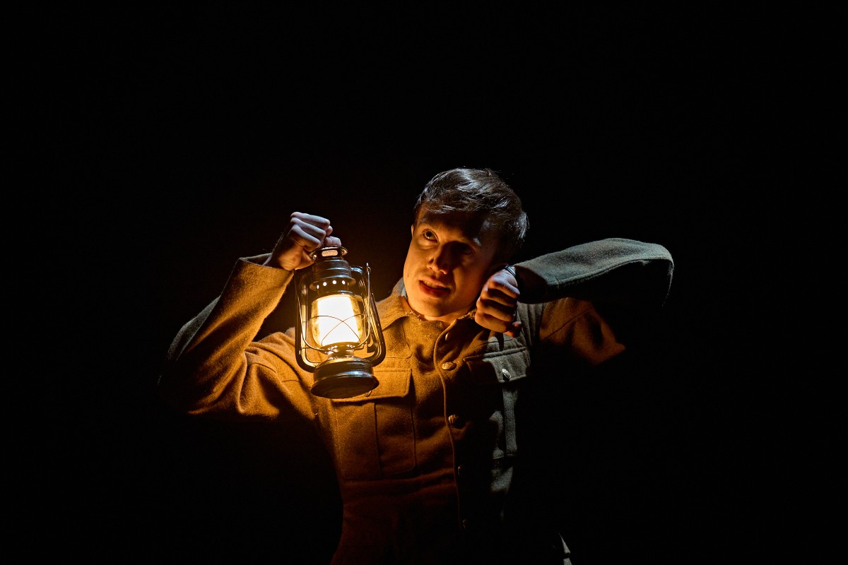 Man holding lamp in the dark listening to a watch