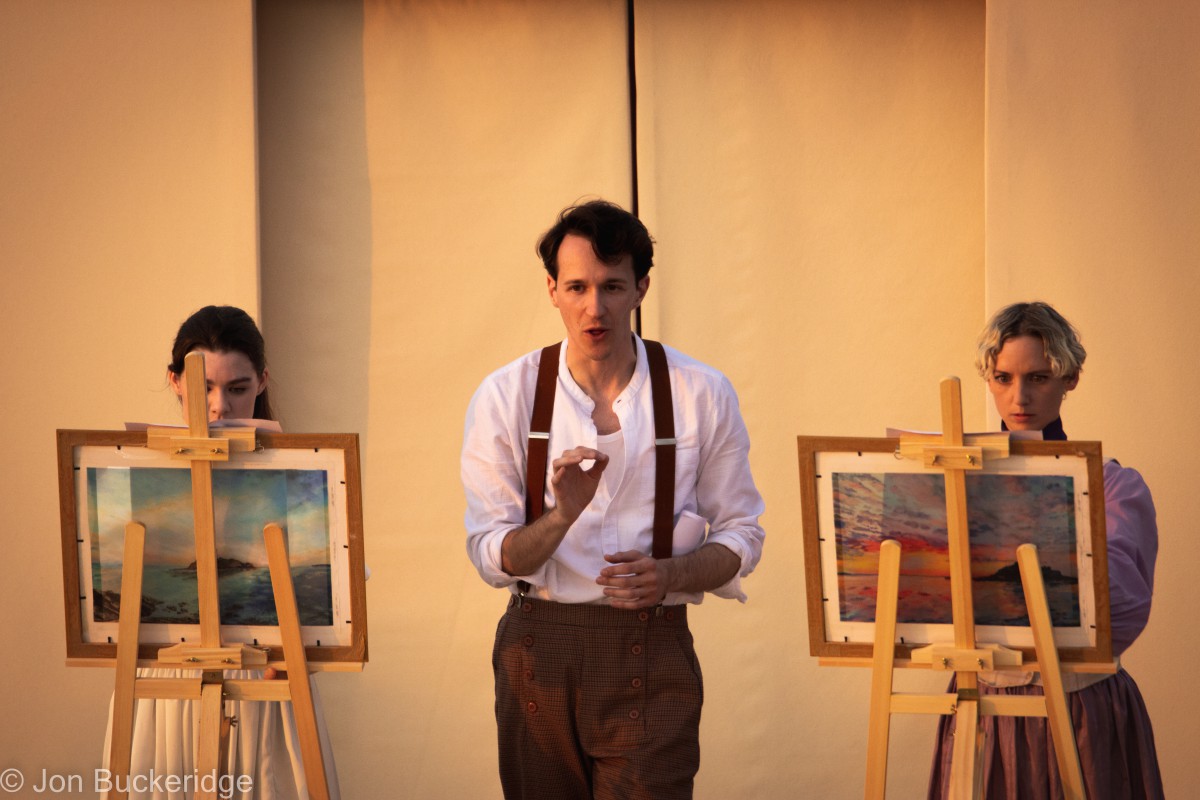 Two woman stand at painting easels either side of a man in a scene from The Women In White