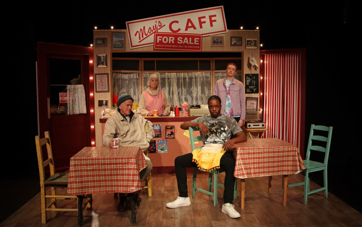 Four people sit in a cafe set for the play Time and Tide
