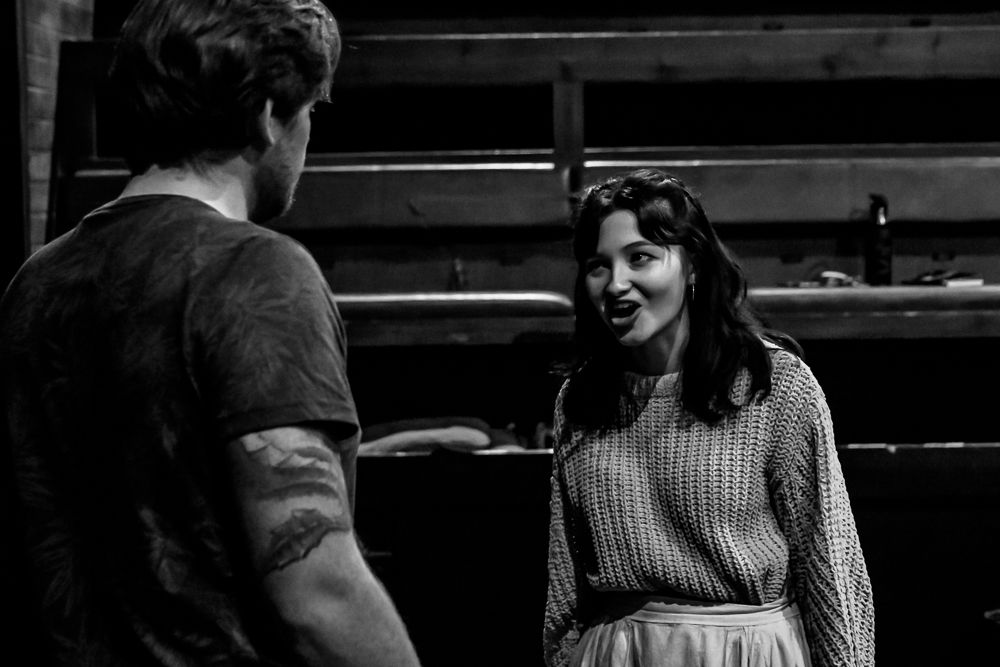 A man and a woman stand in a theatre during rehearsals