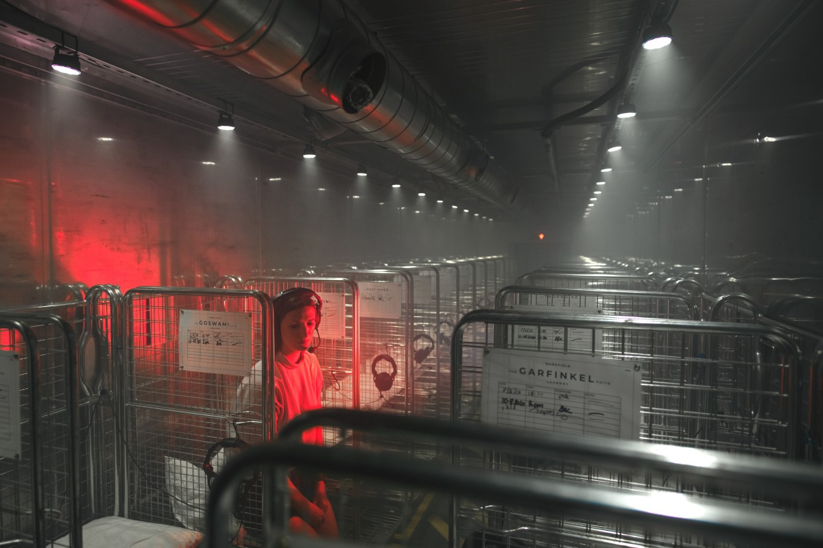 Person sitting in a metal cage in a shipping container