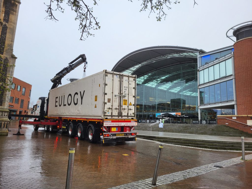 A shipping container being winched into position in front of The Forum building in Norwich