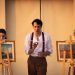 Two woman stand at painting easels either side of a man in a scene from The Women In White